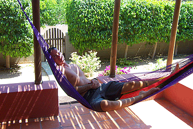 The autor, Jon Ammerman Lies half asleep under the shade of a reed porch in a hammock